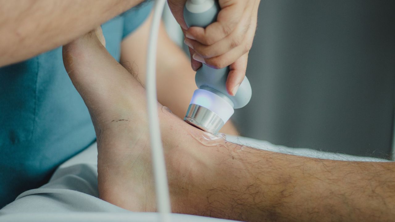 أخصائي علاج طبيعي بيستعمل جهاز علاج على أسفل رجل مريض